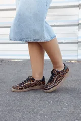 Zapatillas bajas con estampado animal print de leopardo, con cordones negros y suela color caramelo.