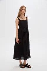 Vestido midi negro de viscosa con cuello cuadrado y tirantes finos ajustables con lazo en los hombros, de corte holgado y diseño fluido.