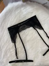 Portaligas de encaje negro con tiras elásticas ajustables y broches metálicos para sujetar medias.