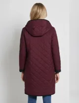 Campera reversible de corte largo con diseño capitoneado. Un lado presenta un tono verde oliva y el otro un tono negro, ambos con cierre frontal mediante botones a presión y bolsillos laterales.