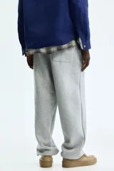 Pantalón deportivo de felpa de mezcla de algodón en color gris melange, con corte relajado, cintura elástica y puños ajustados en los tobillos. Cuenta con bolsillos laterales y cierre decorativo.