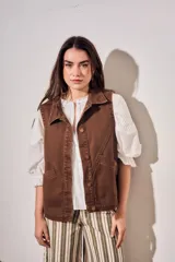 Chaleco oversize de algodón color marrón con efecto lavado, cuello solapa y cierre frontal con botones metálicos. Cuenta con bolsillos frontales diagonales.