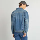 Chaqueta vaquera celeste de corte clásico con cuello camisero, cierre frontal con botones metálicos, bolsillos con solapa abotonada en el pecho y bolsillos laterales.