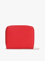 Billetera compacta de poliuretano color rojo, con cierre de cremallera perimetral y herrajes dorados. Presenta el monograma metálico de la marca en la parte frontal y acabado granulado.