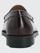 Zapato tipo mocasín de cuero color bordó con acabado brillante, diseño de antifaz clásico y suela de goma con tecnología de amortiguación.