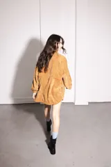 Buzo marrón de pana con cierre frontal parcial, cuello alto, bolsillo tipo canguro con solapa y cordón ajustable en el ruedo.