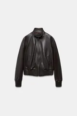 Cazadora tipo bomber de piel 100%, color marrón oscuro, con cuello subido y cierre frontal con cremallera metálica. Cuenta con bolsillos delanteros, forro interior y puños y bajo elásticos acanalados.