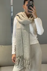 Bufanda de tejido grueso y suave, color blanco, con diseño de flecos en los extremos.