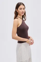 Top de viscosa color marrón, con diseño al cuerpo, escote halter y detalle de cuentas en el cuello.