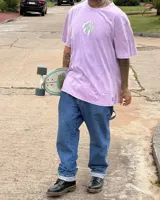 Remera color beige de algodón premium, manga corta y cuello redondo. Presenta un estampado circular en el centro del pecho con un diseño abstracto en tonos grises.