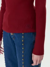 Remera de cuello alto tipo polera, confeccionada en tela rib con textura acanalada y ajuste al cuerpo. Presenta mangas largas y un pequeño bordado distintivo en la parte inferior.