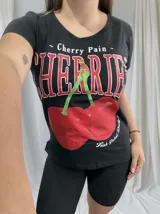 Remera negra de algodón con cuello redondo y estampado de cerezas y texto en rojo y blanco.
