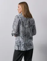 Camisa estampada con hojas en tonos celeste, naranja y verde. Tiene cuello con solapa, abertura central con botones, bolsillos aplicados en la parte delantera y mangas 3/4 con lazo.