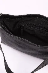 Bandolera de cuero negro con diseño rectangular, caracterizada por una correa ancha decorada con múltiples ojales metálicos y detalles de costuras laterales entrelazadas.