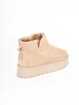 Bota corta tipo ugg con plataforma dentada, confeccionada en material gamuzado color beige con interior forrado en piel sintética.