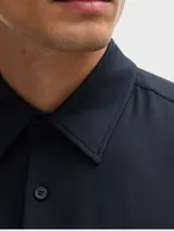 Camisa de vestir BOSS de corte entallado, confeccionada en algodón de alta calidad. Presenta cuello clásico, cierre frontal con botones y mangas largas con puños abotonados.