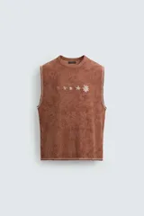 Camiseta tank (sin mangas) de corte relajado, color terracota con efecto lavado y estampado frontal de estrellas en blanco. Presenta cuello redondo y acabados deshilachados en las sisas y el ruedo.