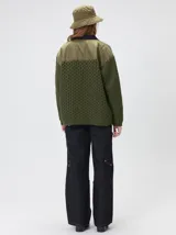Campera tejido grueso y abrigado color verde militar, con forro de nylon interno, cuello estilo camisa en color negro y cierre frontal con botones. Cuenta con cuatro bolsillos delanteros con apliques en distintos tonos y texturas, y un parche bordado circular en el bolsillo superior izquierdo.