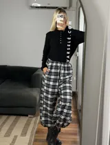Pantalón estilo balloon de tela escocesa, con cintura elástica y cordón ajustable. Presenta un diseño holgado con puños elásticos en los tobillos.