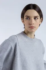Sweater gris de punto con cuello redondo, mangas amplias y terminaciones acanaladas.