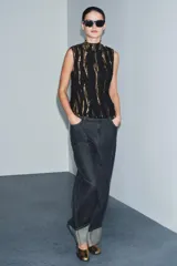 Top sin mangas de cuello perkins, confeccionado en tejido negro con aplicaciones de lentejuelas y detalles de hilo metalizado en tonos dorados. Presenta un diseño estructurado con cierre en la espalda.