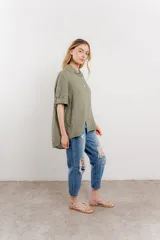 Camisa de lino color verde militar, de corte amplio y caída ligera. Cuenta con cuello camisero, botones en el frente y mangas 3/4 que se pueden arremangar.