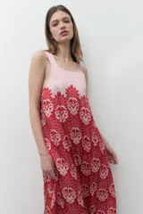 Maxi vestido con breteles finos, corte recto y estampado floral en tonos rojo y blanco sobre fondo rosa pálido.