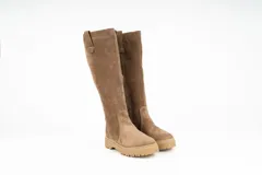 Bota de caña alta confeccionada en cuero nobuck color marrón, con suela track dentada y detalle de tirador en la parte superior de la caña.