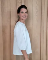 Remera blanca de algodón con cuello redondo, mangas tres cuartos abullonadas y detalle de volados en los hombros.