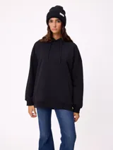 Gorro tipo beanie de punto acanalado color bordó, con etiqueta rectangular blanca con logo de la marca en el frente.