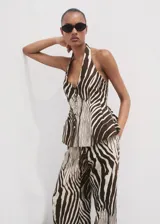 Pantalón wide leg de tiro medio con estampado de cebra, confeccionado en mezcla de lino y algodón. Cuenta con bolsillos laterales, trabillas para cinturón y cierre frontal oculto con botón, gancho y cremallera.