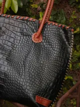 Bolso shopper de cuero azul con textura crocco, manijas largas marrones y costuras artesanales visibles en los bordes.