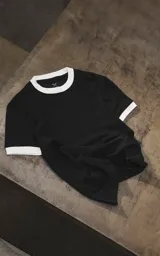 Remera negra de manga corta con cuello redondo y ribetes blancos contrastantes en cuello y puños.