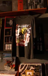Remera de manga corta con cuello redondo y calce oversize, color negro con efecto nevado. Presenta un estampado gráfico frontal con el logo de la banda The Prodigy y elementos artísticos.