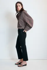 Jeans de tiro alto con cinco bolsillos, diseño cropped flare y bajo sin costuras. Cuenta con cierre frontal de cremallera y botón metálico.