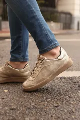 Sneaker de diseño artesanal en color dorado con acabado metalizado, cordones al tono y suela de goma color suela.