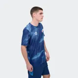 Remera deportiva Umbro modelo Press, de color rojo con un estampado abstracto en tonos más oscuros, cuello redondo y manga corta. Incluye el logo de la marca en el pecho y el escudo del Club Nacional de Football.