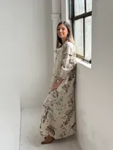 Vestido largo beige con diseño estampado de flores, cuello redondo amplio y mangas largas holgadas.