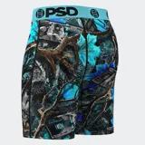 Calzoncillos bóxer estampados con billetes de 100 dólares, hojas de arce y ramas de árbol en tonos azules, negros y grises. Cintura elástica celeste con logo de la marca en negro.