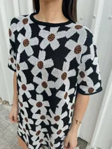 Vestido corto negro con estampado de flores blancas y marrones, de corte holgado y manga corta.