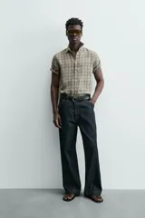 Camisa de lino color beige de corte relajado, con cuello solapa, manga corta y cierre frontal con botones.