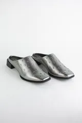 Zueco de cuero color bronce con punta almendrada y detalle de tachas metálicas doradas en toda la capellada. Posee un taco cuadrado bajo de 3 cm.