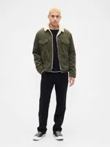 Campera de pana color verde oliva con interior y cuello de corderito sintético. Presenta cierre frontal con botones metálicos, bolsillos en el pecho con solapa y botones, y puños ajustables.