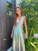 Vestido largo con escote en V, estampado en tonos rojizos y rosados, con un patrón ondulado. Presenta cut-outs laterales bajo el busto y breteles finos que se cruzan en la espalda.