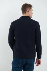 Cardigan tejido color azul marino, con cuello y solapa, cierre frontal de botones y bolsillos delanteros. Presenta un tejido de punto con textura.