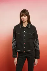 Campera de jean con lavado oscuro rojizo/marrón, estilo trucker. Presenta tachas doradas a lo largo de los bordes de los bolsillos, el canesú y los puños. Posee un bordado en relieve de diseño floral en la manga.