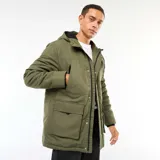 Parka color verde militar con capucha, cierre frontal con cremallera y botones a presión. Cuenta con bolsillos laterales con cierre y bolsillos frontales tipo cargo con solapa.
