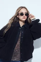 Campera de corderito color marrón oscuro, con cuello camisero y cartera frontal en tela lisa a tono. Presenta cierre mediante botones a presión y mangas largas con puños elásticos.