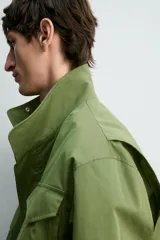 Parka estilo militar color verde, de corte relaxed fit, cuello subido y manga larga. Cuenta con bolsillos de plastrón con solapa en el pecho y en la cadera, cintura ajustable con cordón interior y cierre frontal con cremallera oculta por solapa con botones a presión.