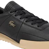 Championes Lacoste modelo Aura, de cuero negro con textura granulada, cordones al tono y suela de goma en color beige. Presenta el logo del cocodrilo metálico en el lateral.